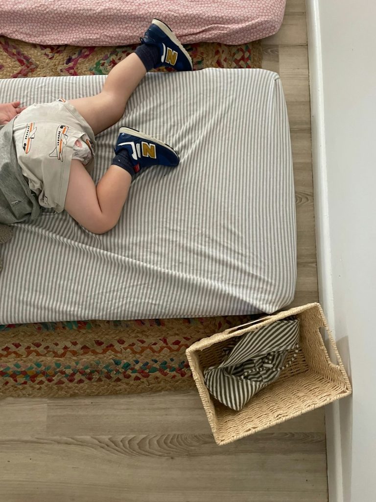 a-baby-laying-on-a-bed-with-a-pair-of-shoes-c4dk1twsvbw