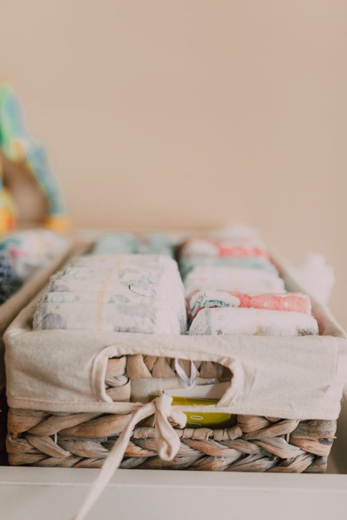Close-up of a woven basket with neatly arranged baby diapers in a neutral-toned nursery.