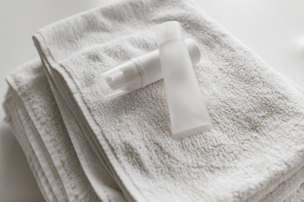 Clean and simple display of white skincare bottles on a towel, perfect for self-care themes.